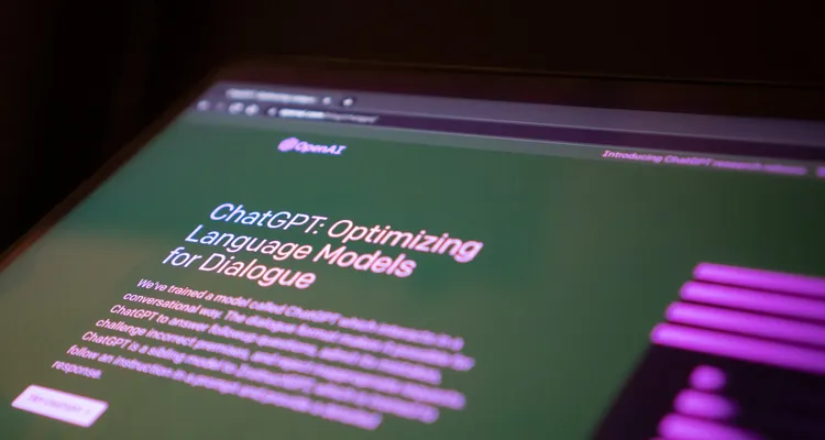 A close up of a computer screen showing the OpenAI website with a blurry background