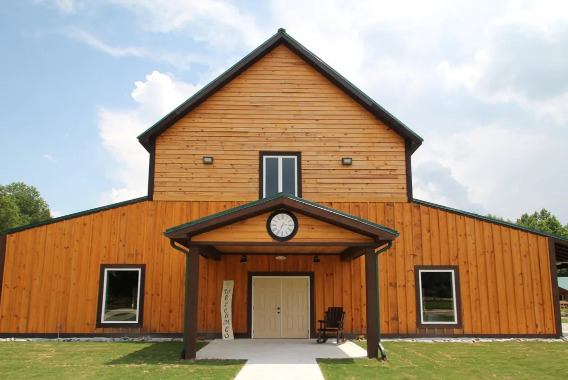 A wooden barn with a porch which has a clock facing forward