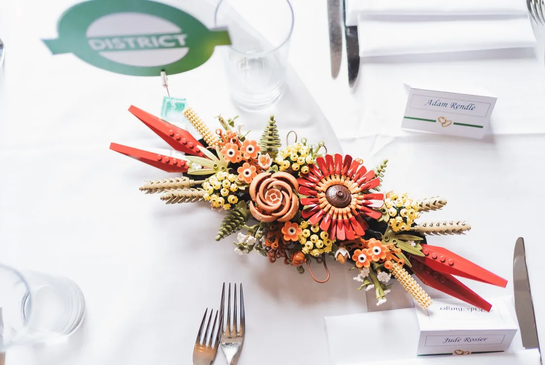 Wedding table set up with handmade place names, District Line roundal table name and Lego flowers with silver cutlery and clear glassware on white table linen