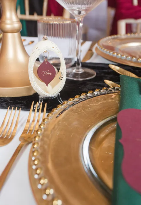A table setup with gold plates and cutlery with a nameplate