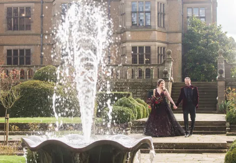 A couple outside a gothic hall with a fountain in front