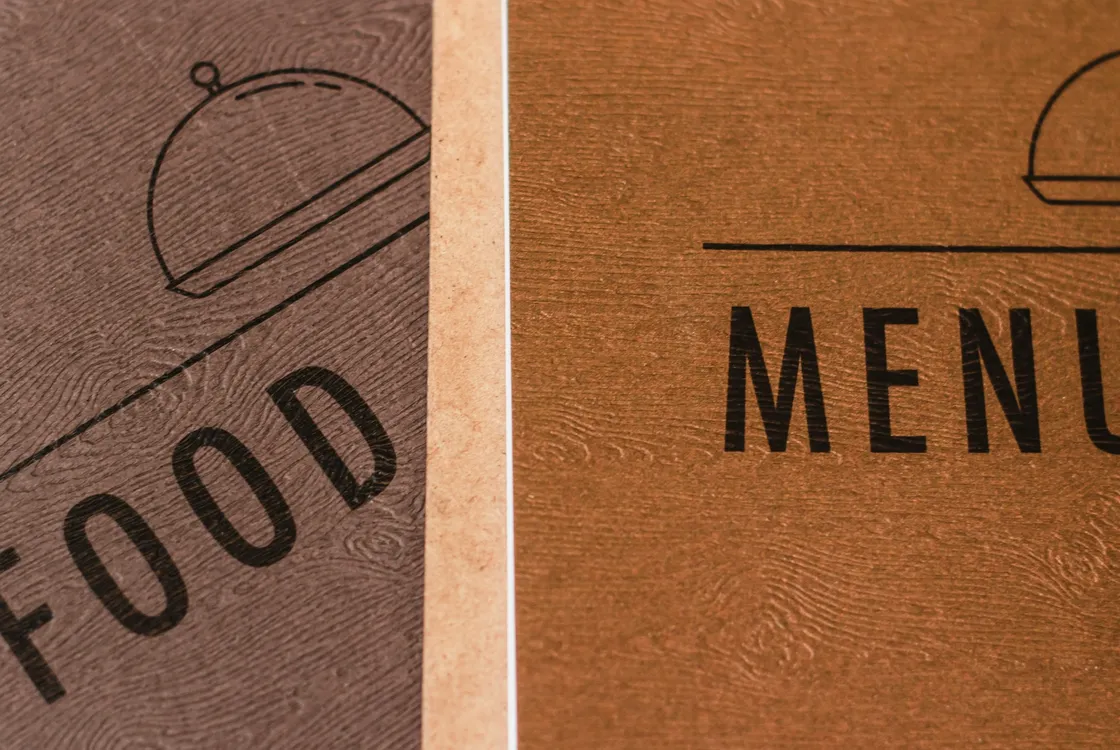 Two menus overlapping, one saying food, one saying menu, in two shades of a brown wood effect