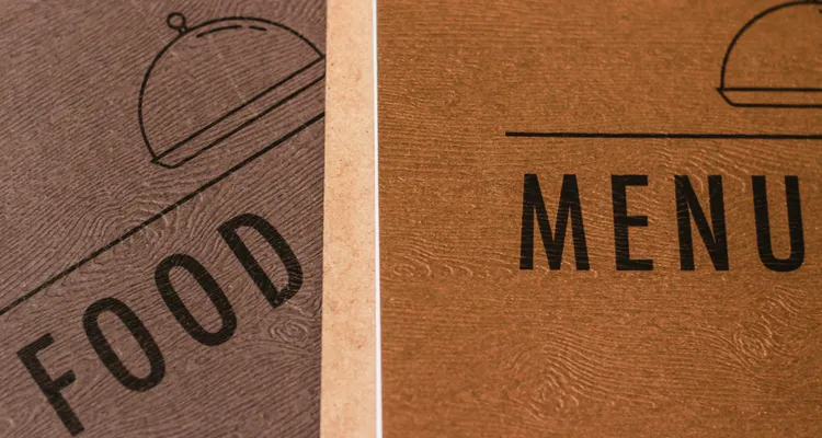 Two menus overlapping, one saying food, one saying menu, in two shades of a brown wood effect