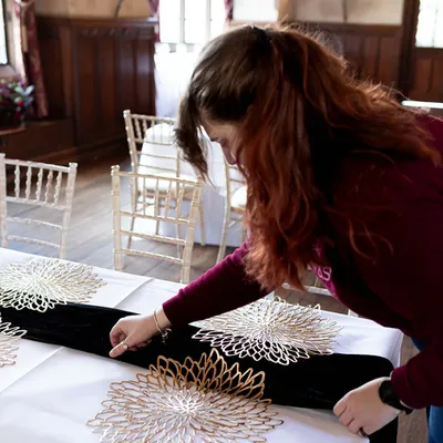 Rachel adjusting a black table runner on a white cloth
