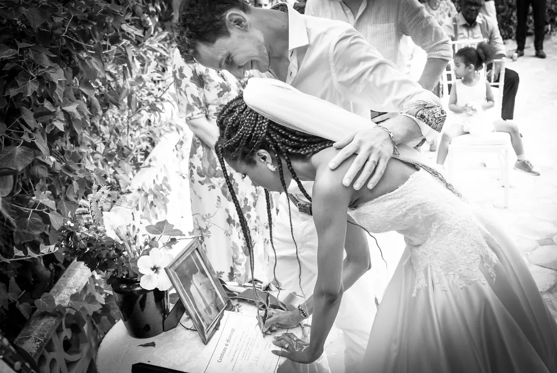 A black and white image of a newly married couple signing their certificate of marriage